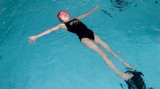 Foto: una bambina galleggia nell'acqua con la braccia aperte lateralmente e le gambe tese