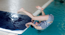 Foto: una bambina esegue una capriola in avanti dal bordo della piscina