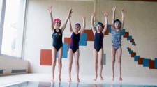 Foto: quattro bambini saltano in estensione dal bordo della piscina
