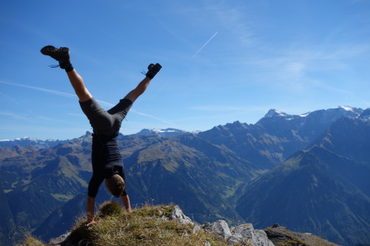 Un uomo esegue una verticale in cima a una montagna
