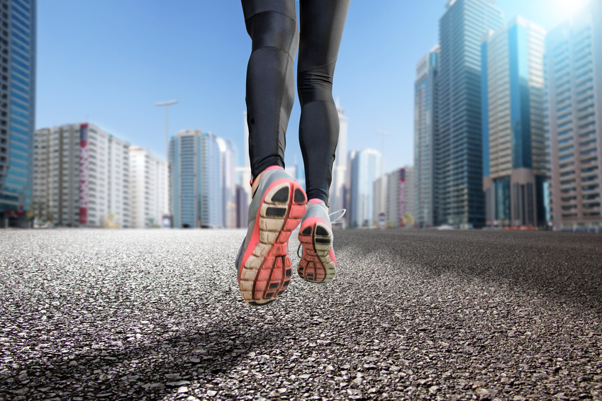 Gros plan sur les jambes d'une personnes faisant un jogging dans une ville.