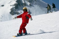 Un bambino fa snowboard su un pendio lievemente inclinato