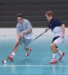 Zwei Unihockey-Spieler duellieren sich.