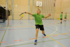 Un garçon frappe un volant de badminton en revers.