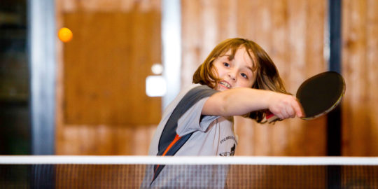 Un bambino colpisce una pallina da tennis tavolo di diritto