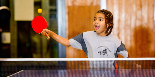 Une jeune fille frappe une balle de tennis de table en coup droit.