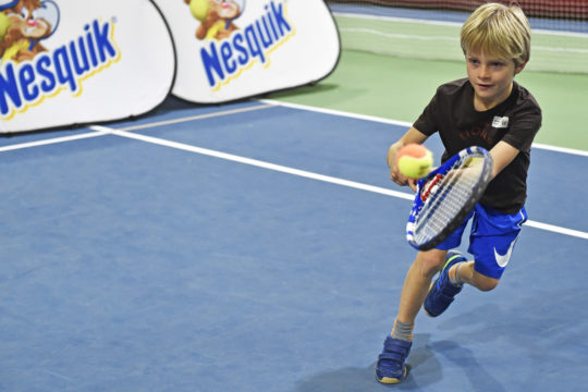 Foto: Junge bei einem Return im Tennis.