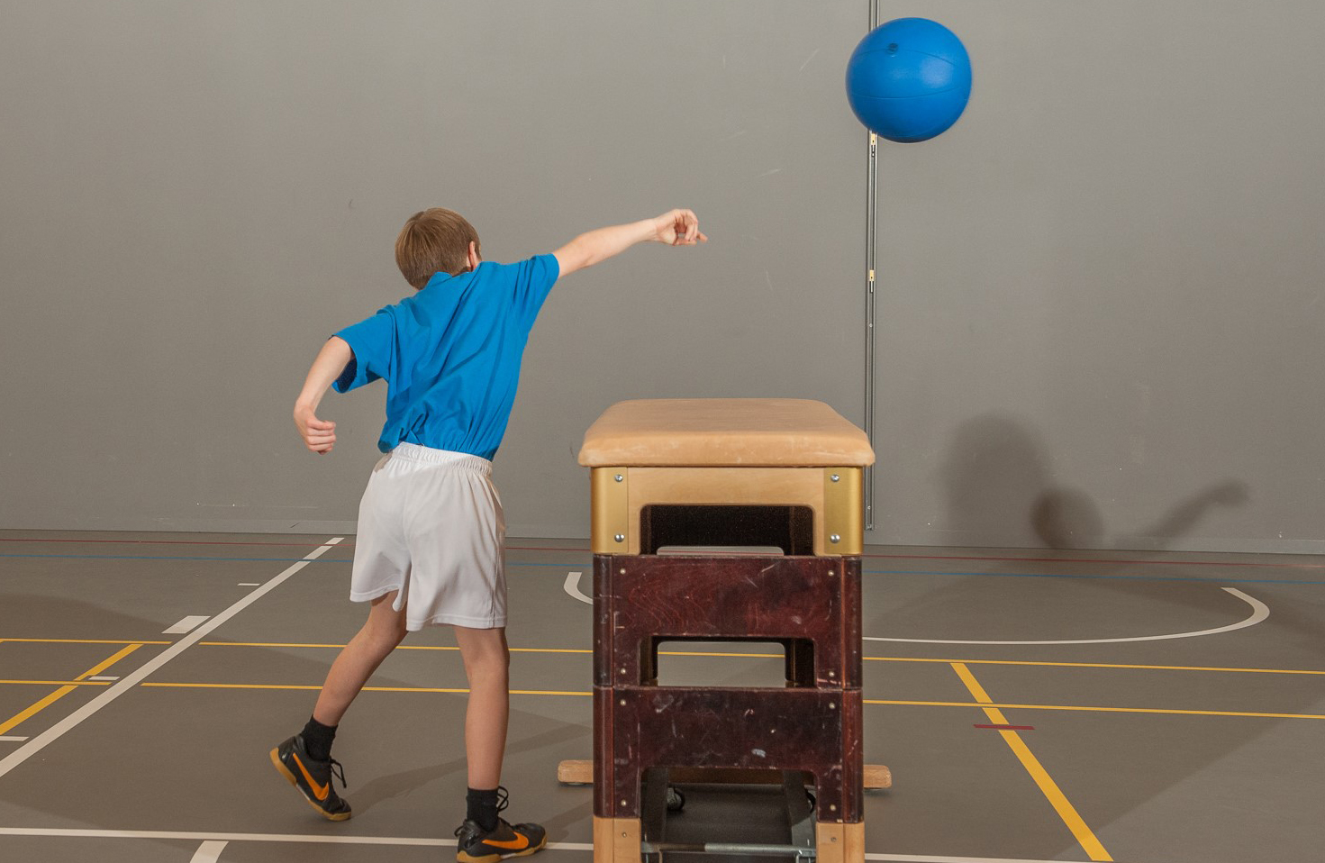 Photo: un jeune lance un ballon lourd par-dessus un caisson.