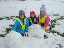 Drei Kinder mit grossen Schneekugeln.