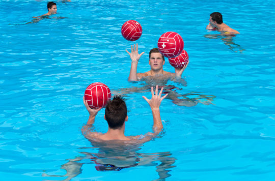 Foto: due giovani in acqua mentre si passano dei palloni