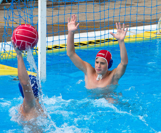 Foto: un portiere di pallanuoto con le braccia sollevate davanti a un avversario