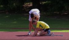 Un  moniteur donne des conseils à un jeune athlète en position de départ dans les starting-blocks.