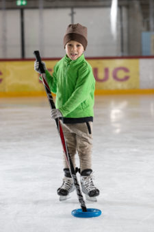 Foto: un bambino spinge un anello di plastica con un bastone da hockey