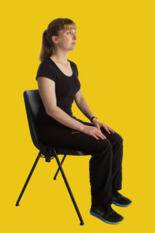 Frau sitzt auf Stuhl und entspannt sich.