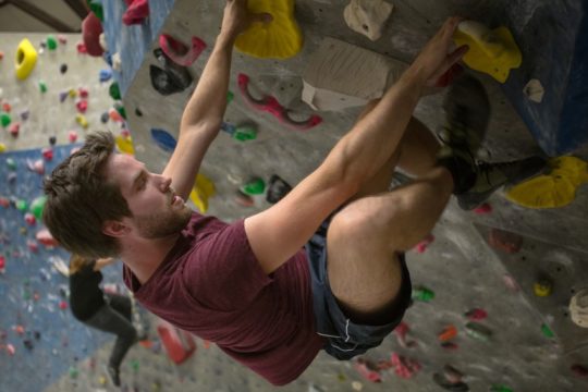 Foto: Mann an einer Kletterwand in der Halle.