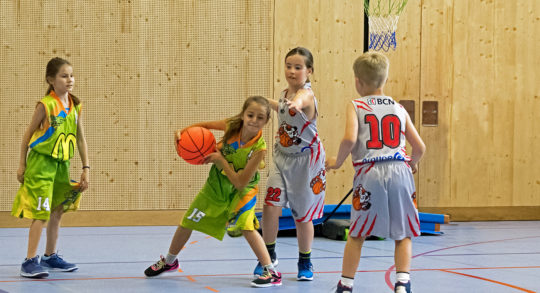 Foto: quattro bambini sono impegnati in una partita di pallacanestro