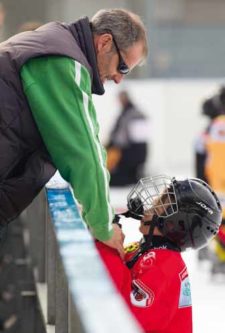 Photo: Un père souriant encourage son hockeyeur de fils.