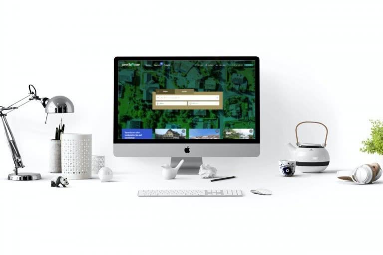 Schreibtisch mit Desktop auf dessen Bildschirm die Startseite von newhome angezeigt wird.