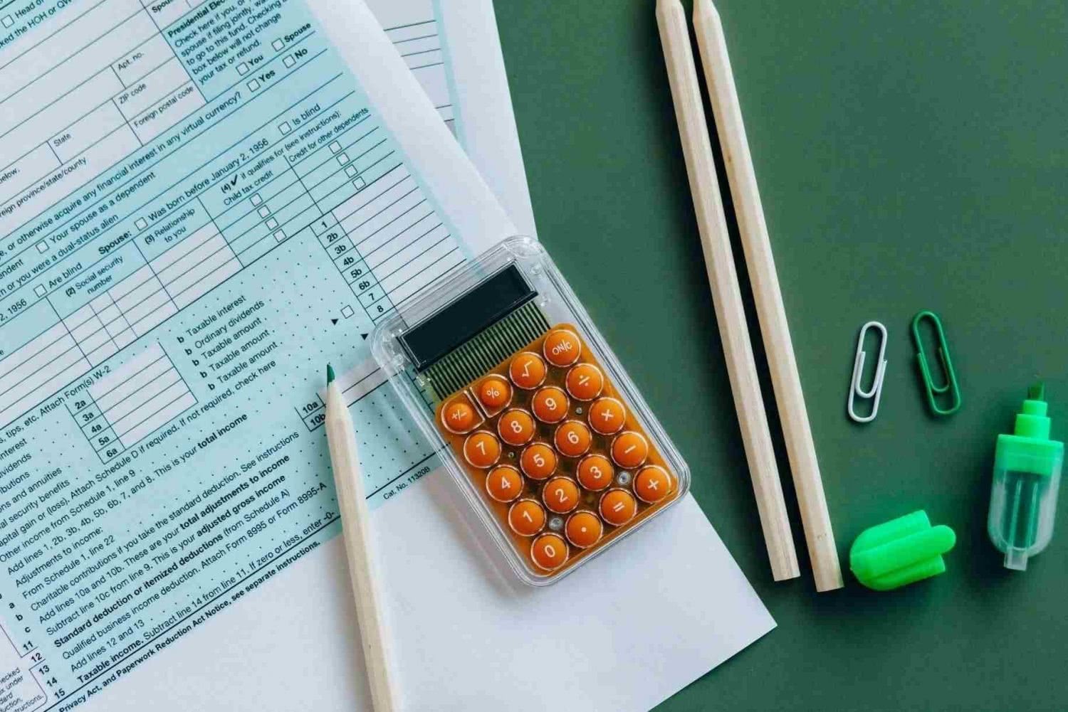 Dichiarazione dei redditi, calcolatrice, pennarelli e penne su una scrivania