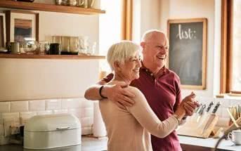 Man sieht ein älteres Paar in einer Küche, sie sind fröhlich und Tanzen.